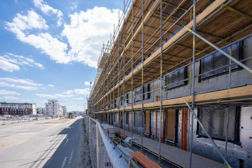 Scaffolding on building facade at urban construction site under bright blue sky.